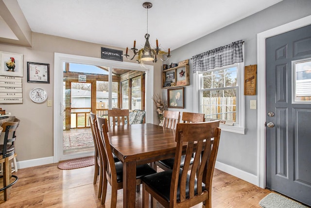 dining space featuring baseboards, light wood finished floors, and an inviting chandelier