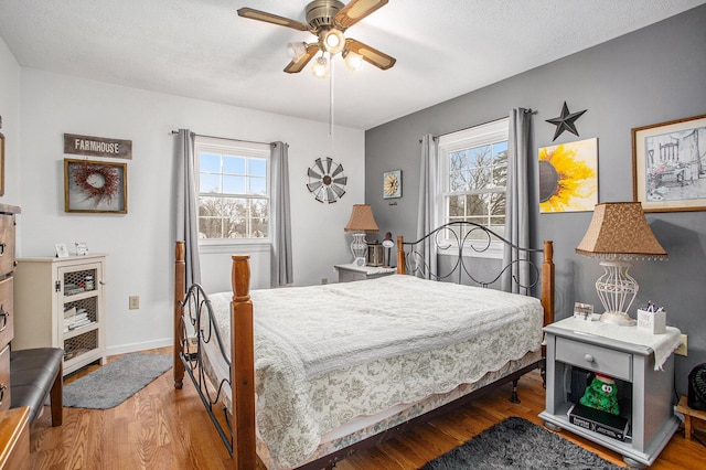 bedroom with ceiling fan, wood finished floors, and baseboards