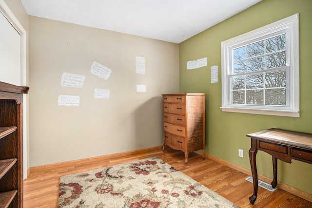 living area with light wood finished floors, visible vents, and baseboards