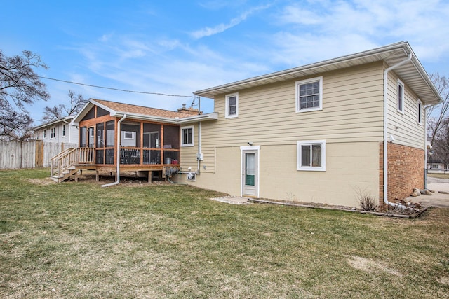 rear view of house featuring a lawn, fence, and a sunroom