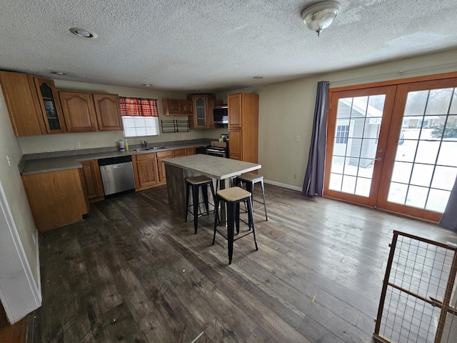 kitchen featuring french doors, a kitchen bar, a center island, stainless steel dishwasher, and dark hardwood / wood-style floors