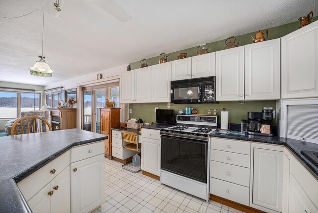 12118 N Sherman Lake Dr, Augusta, MI 49012 - kitchen with pendant lighting, dark countertops, gas range oven, white cabinets, and black microwave