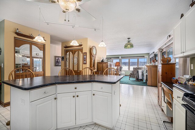 12118 N Sherman Lake Dr, Augusta, MI 49012 - kitchen with decorative light fixtures, a kitchen island, dark countertops, and white cabinetry