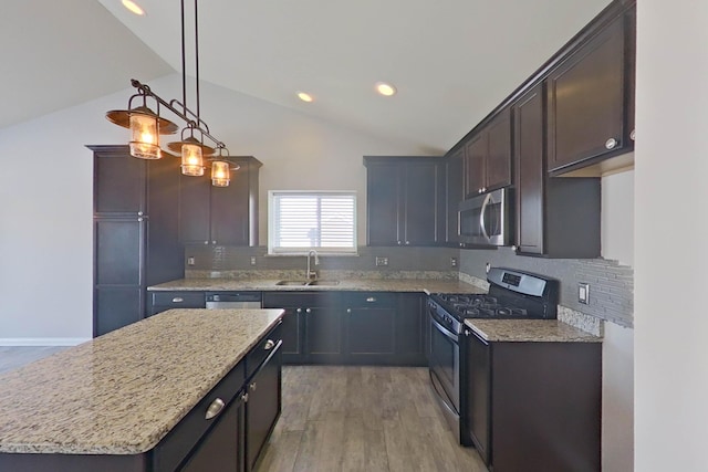 kitchen featuring light stone countertops, vaulted ceiling, stainless steel appliances, light wood-type flooring, and a sink