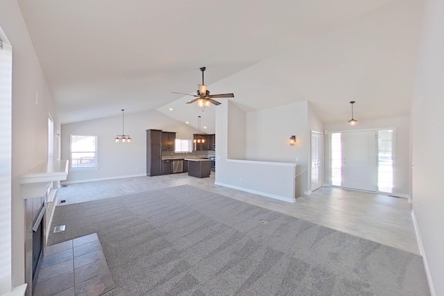 unfurnished living room featuring high vaulted ceiling, light wood-style flooring, recessed lighting, ceiling fan with notable chandelier, and baseboards