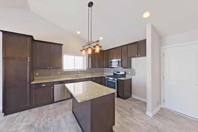 kitchen featuring dark brown cabinetry, decorative backsplash, appliances with stainless steel finishes, vaulted ceiling, and a sink