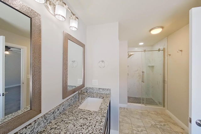 bathroom featuring a marble finish shower, vanity, and baseboards