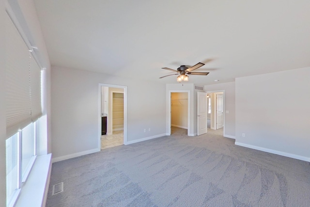 unfurnished bedroom with light carpet, visible vents, a spacious closet, and baseboards