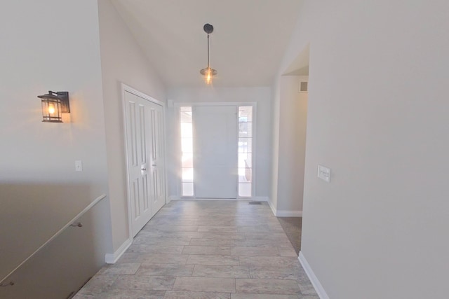 foyer entrance with lofted ceiling, visible vents, and baseboards