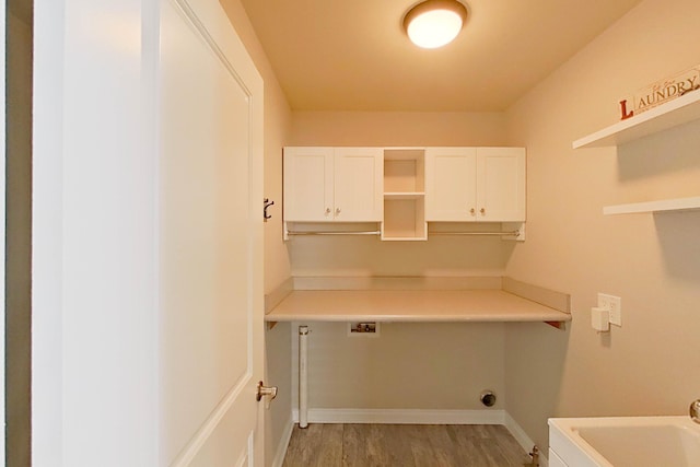 clothes washing area featuring light wood-type flooring, hookup for a washing machine, cabinet space, and baseboards