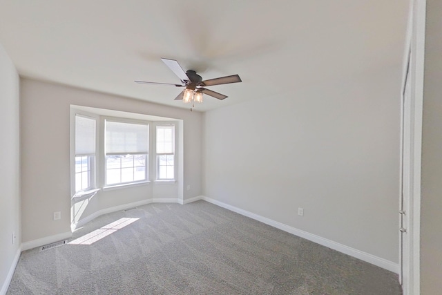 carpeted empty room featuring baseboards, visible vents, and a ceiling fan