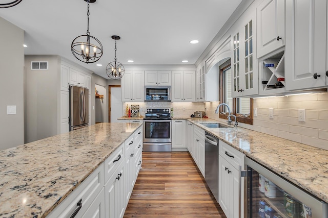 kitchen with sink, hanging light fixtures, stainless steel appliances, wine cooler, and white cabinets