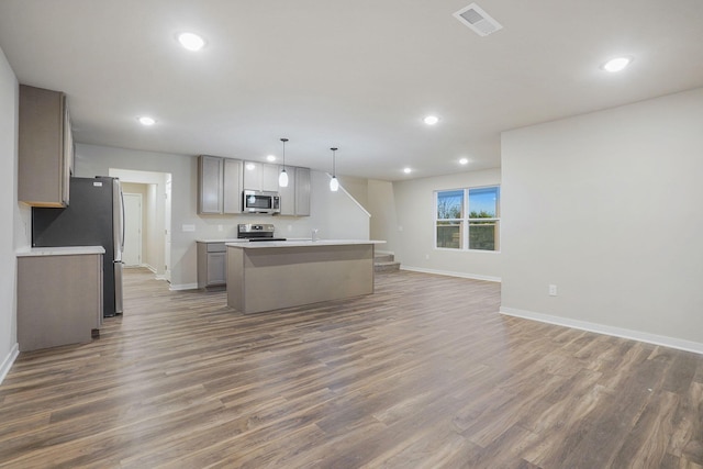 kitchen featuring dark wood-type flooring, gray cabinetry, hanging light fixtures, appliances with stainless steel finishes, and a kitchen island