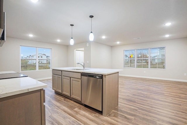 kitchen with sink, dishwasher, a kitchen island with sink, light hardwood / wood-style floors, and decorative light fixtures