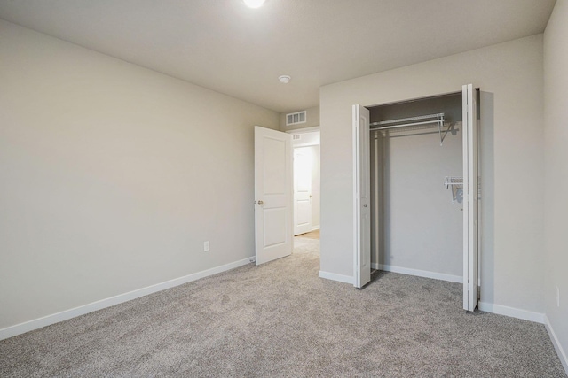 unfurnished bedroom with light colored carpet and a closet