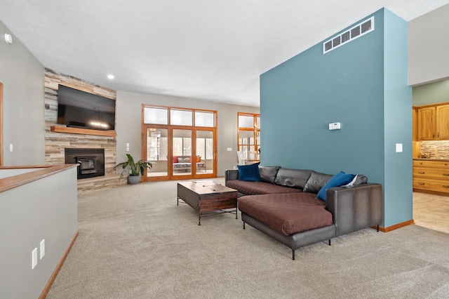 carpeted living area featuring a stone fireplace, visible vents, and baseboards