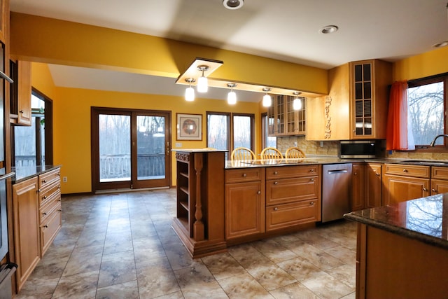 kitchen with sink, dishwasher, backsplash, kitchen peninsula, and dark stone counters