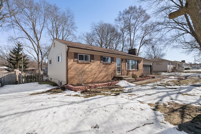 view of front of home featuring a garage, a chimney, fence, and brick siding