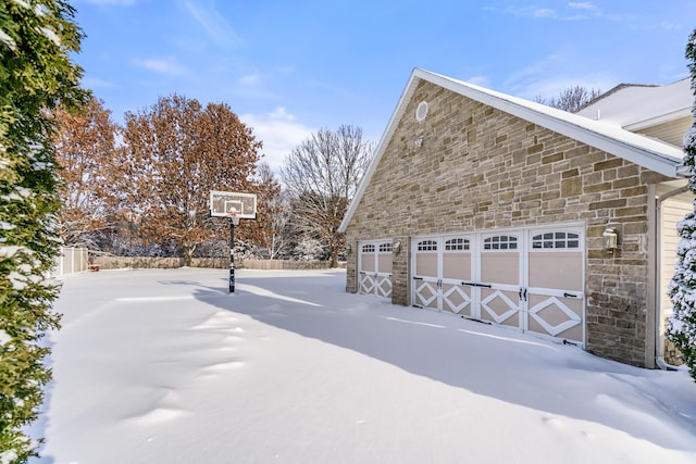 snow covered property featuring a garage and an outdoor structure