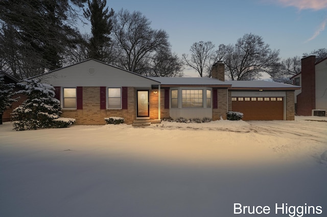 ranch-style house with a garage, a chimney, and brick siding