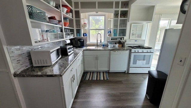 kitchen with dark wood-type flooring, sink, white cabinetry, dark stone countertops, and white appliances