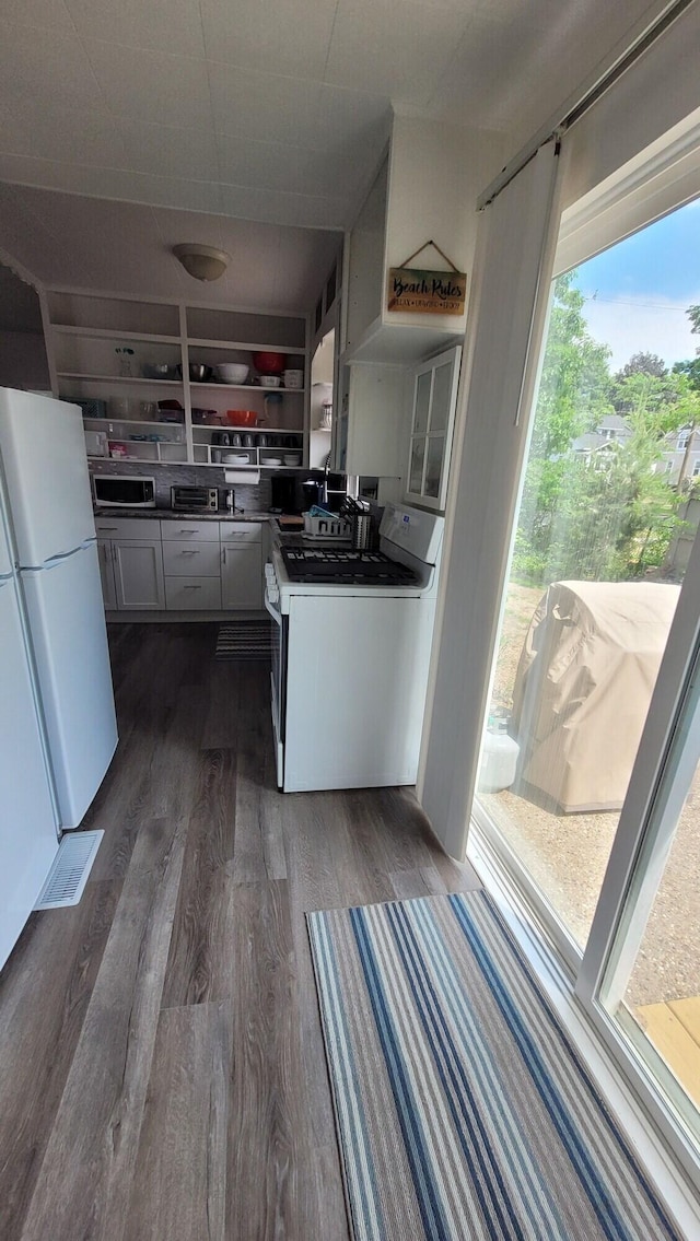 kitchen with white appliances, dark wood-type flooring, and white cabinets