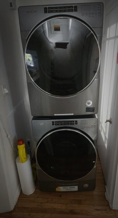 laundry area featuring stacked washing maching and dryer and hardwood / wood-style floors