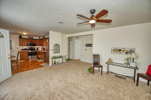 sitting room featuring ceiling fan, carpet floors, and a textured ceiling