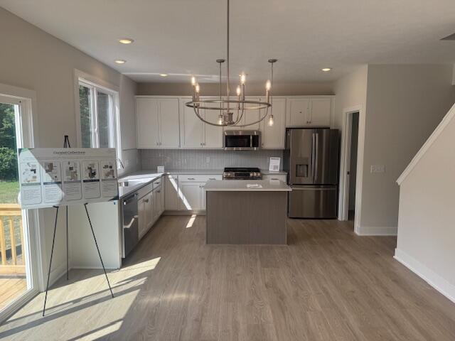 1967 Lowe Dr, Spring Lake, MI 49456 - kitchen with stainless steel appliances, a center island, tasteful backsplash, white cabinetry, and a chandelier