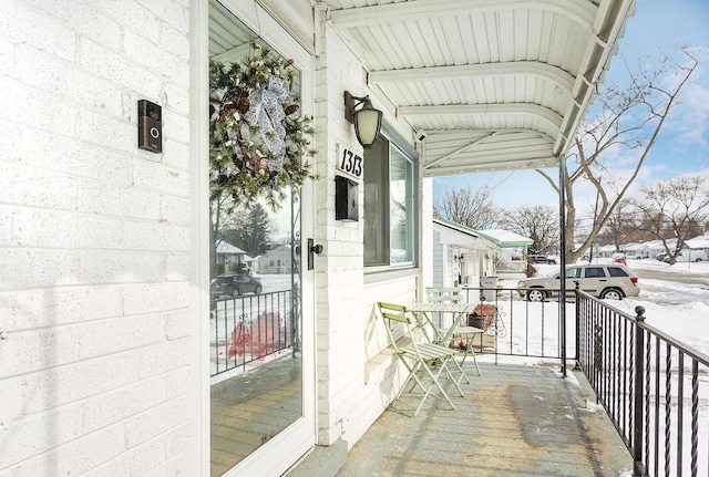 snow covered back of property featuring a porch