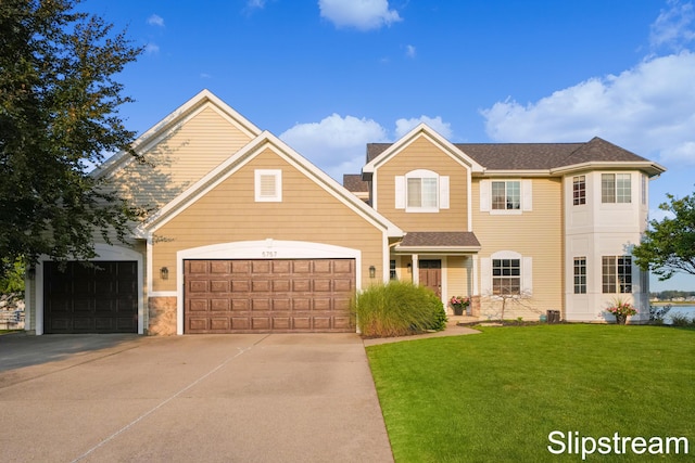 traditional-style house with an attached garage, a front lawn, and concrete driveway