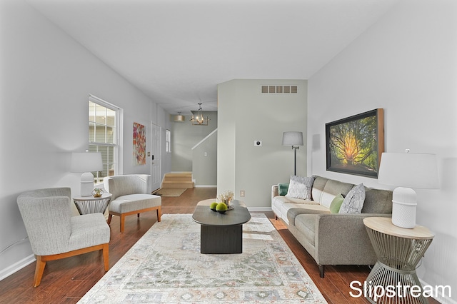 living room with visible vents, stairway, baseboards, and wood finished floors