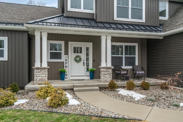 view of exterior entry featuring roof with shingles, a porch, board and batten siding, a standing seam roof, and metal roof