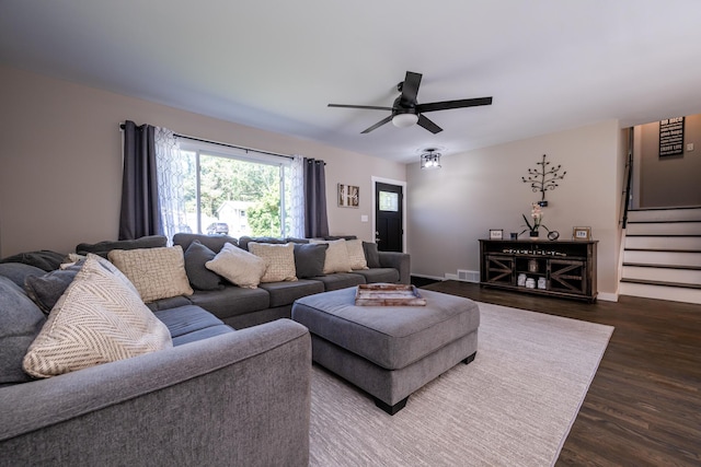 living area featuring visible vents, baseboards, dark wood finished floors, ceiling fan, and stairs