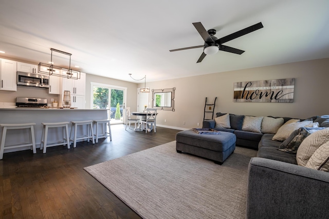 living room with dark wood-style flooring, a ceiling fan, and baseboards