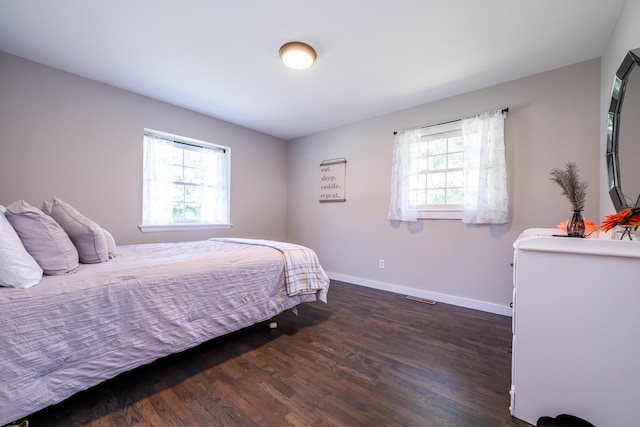 bedroom with dark wood-style flooring, multiple windows, and baseboards