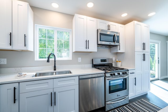 kitchen featuring light stone counters, recessed lighting, stainless steel appliances, a sink, and white cabinetry