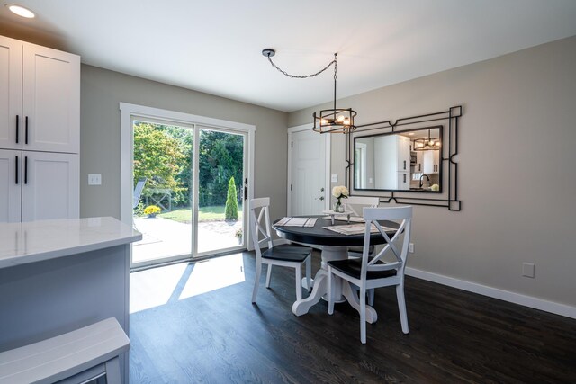 dining room featuring dark wood-type flooring, a chandelier, and baseboards