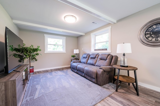 living room with baseboards, visible vents, beamed ceiling, and wood finished floors