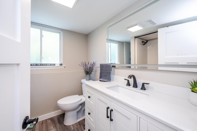 full bath with baseboards, visible vents, toilet, wood finished floors, and vanity