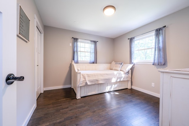 bedroom with multiple windows, dark wood finished floors, and baseboards