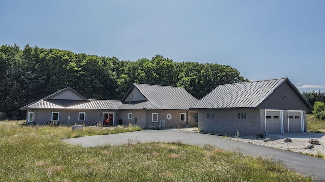 view of front of home with a garage, a standing seam roof, metal roof, and driveway