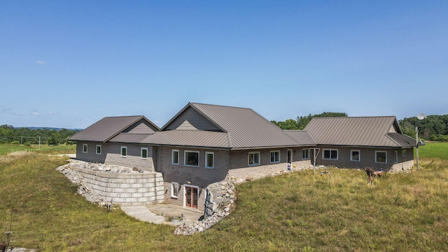 rear view of property with metal roof and a yard