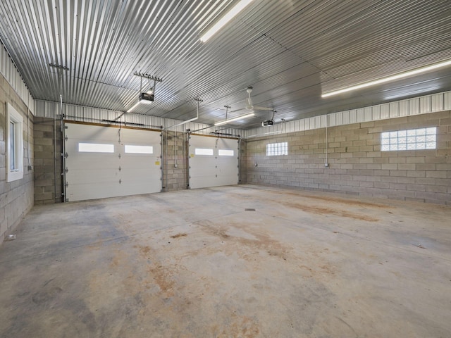 garage with concrete block wall, metal wall, and a garage door opener