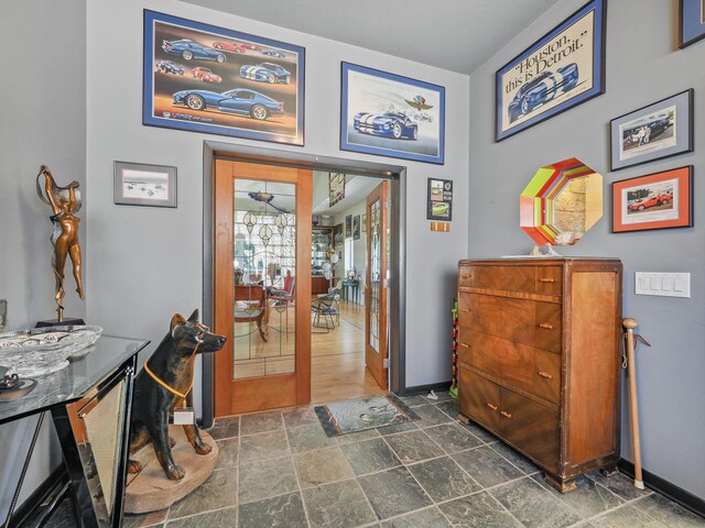 interior space featuring french doors, stone finish flooring, and baseboards