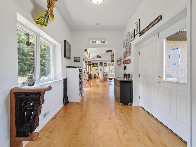 foyer with light wood-style floors, visible vents, and arched walkways