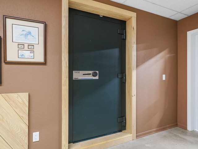 interior details featuring baseboards, concrete flooring, and a drop ceiling