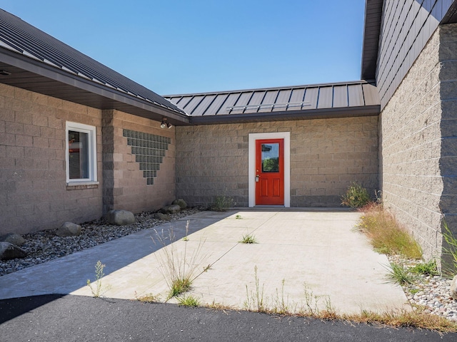 doorway to property with a standing seam roof, metal roof, and concrete block siding