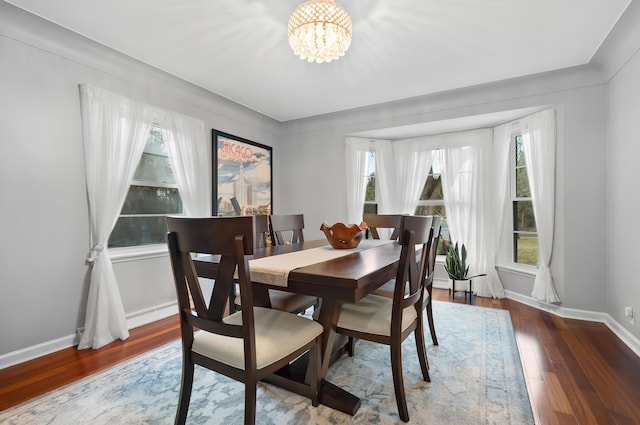 dining area featuring wood-type flooring, a chandelier, and baseboards