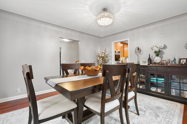 dining room featuring light wood-style floors, baseboards, and an inviting chandelier